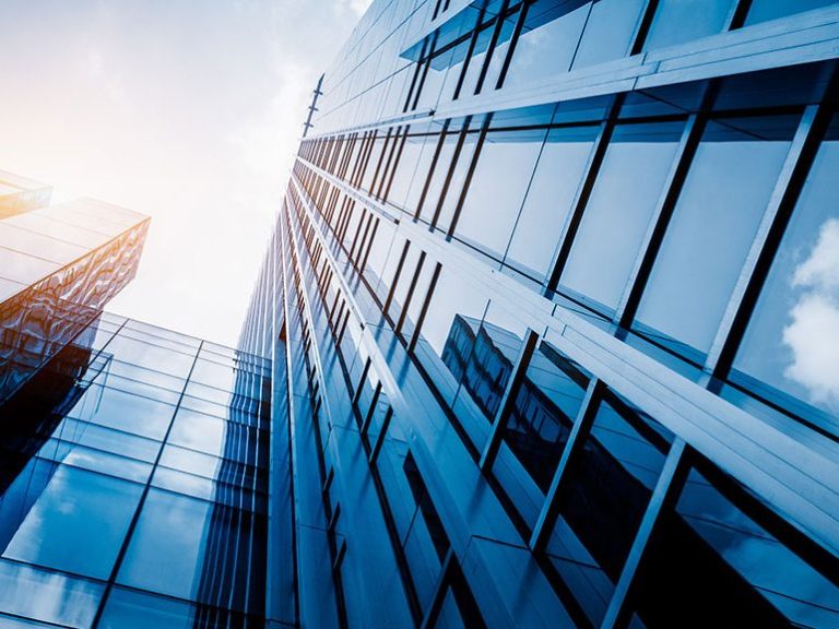 Objektbetreuung Hände umschließen ein Modellhaus, symbolisieren Schutz und Sicherheit.